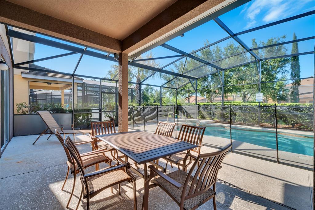 A screened-in patio features a dining set, lounge chair, and a private swimming pool — 4328 ACORN COURT, DAVENPORT, FL