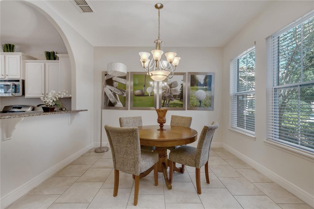 A dining area features a round wooden table, four chairs, and golf-themed wall art — 4328 ACORN COURT, DAVENPORT, FL