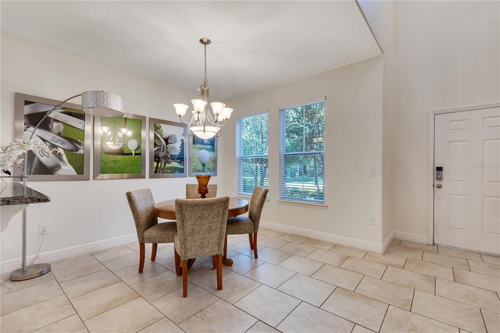 A dining area features a round table, four chairs, a chandelier, and golf-themed wall art — 4328 ACORN COURT, DAVENPORT, FL