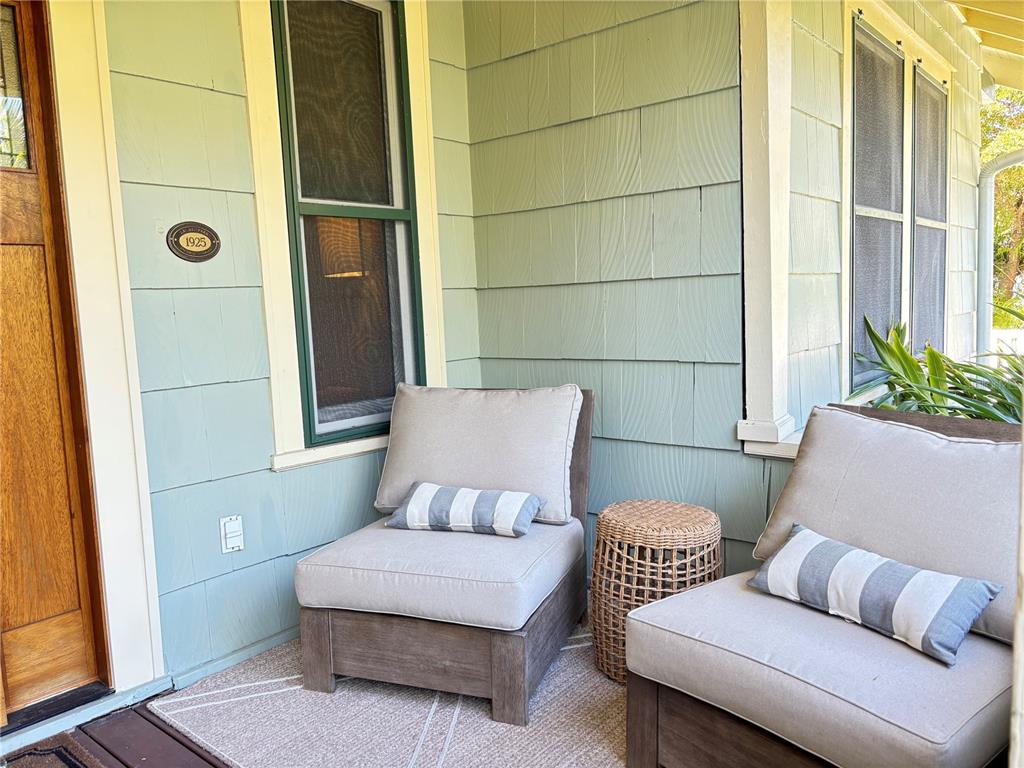 A covered porch features light blue siding, two armchairs with striped pillows, and a side table — 324 JULIA PLACE, SARASOTA, FL