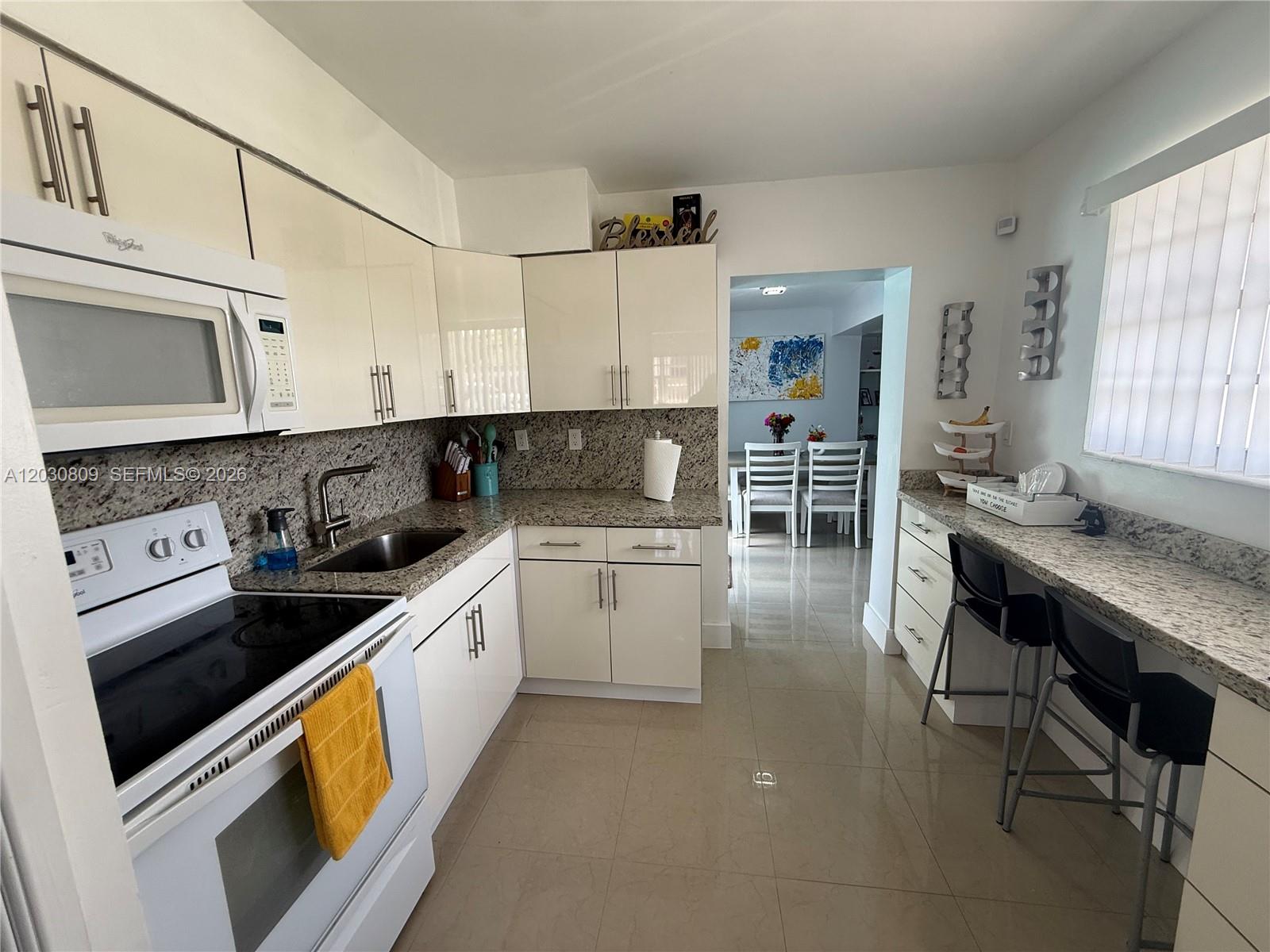 A kitchen features white cabinets, granite countertops, stainless steel appliances, and a breakfast bar — 10030 SW 213th Ter, Cutler Bay FL 33189, CUTLER BAY, FL