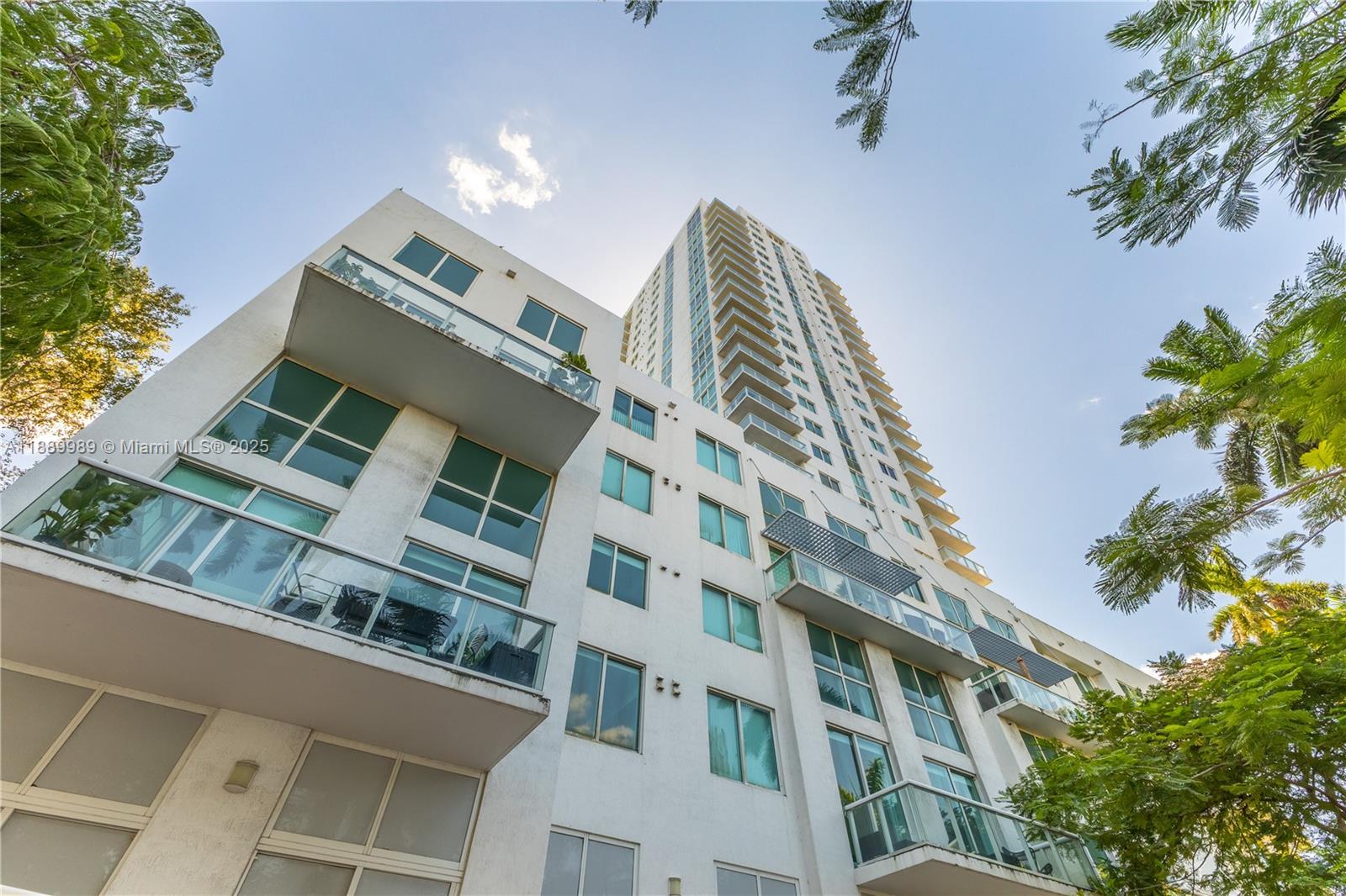 A low-angle view shows the exterior facade of a multi-story white residential building — 1861 NW S River Dr # 406, Miami FL 33125, MIAMI, FL