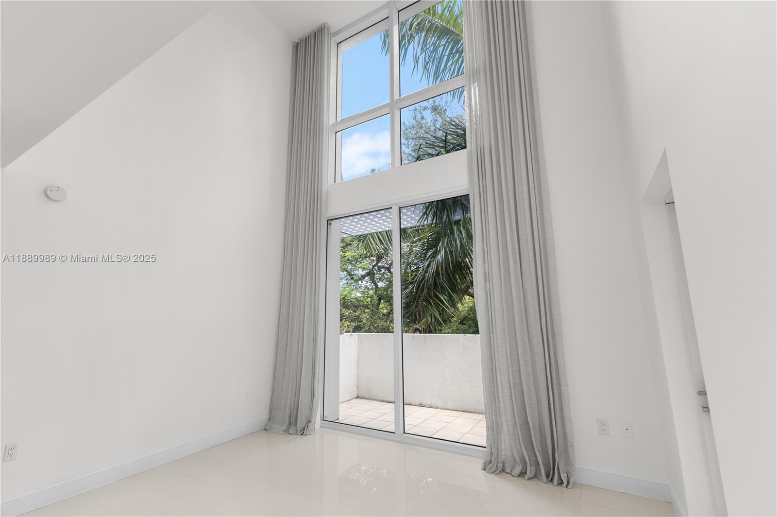 A bright, minimalist room features high ceilings, floor-to-ceiling windows, and a sliding glass door — 1861 NW S River Dr # 406, Miami FL 33125, MIAMI, FL