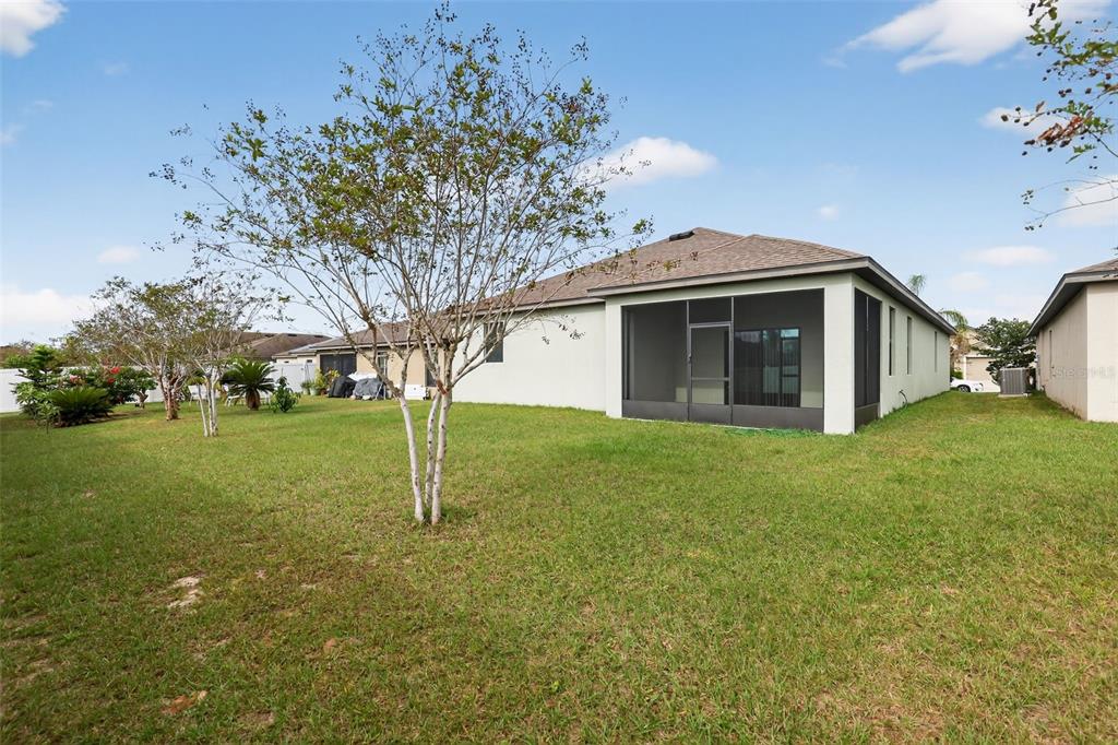 A backyard view of a house with a screened-in patio and a grassy lawn — 508 DELTA AVENUE, GROVELAND, FL