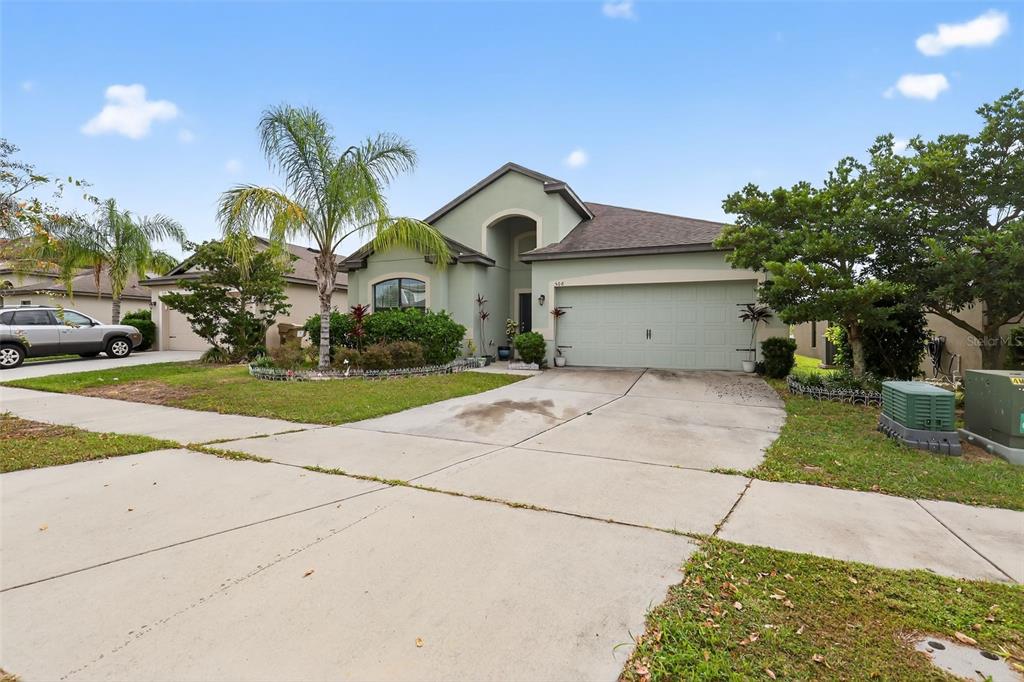 A single-story house with a light green exterior, a two-car garage, and a palm tree — 508 DELTA AVENUE, GROVELAND, FL
