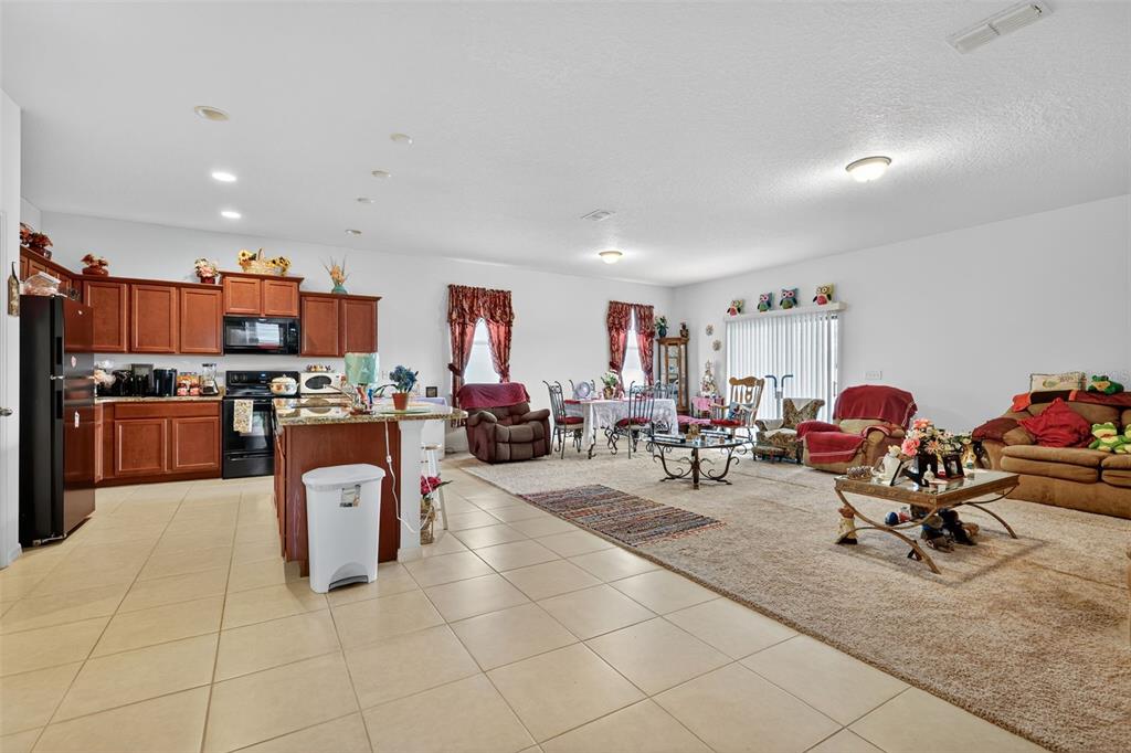 An open-concept kitchen with wood cabinets and an island flows into a carpeted living area — 508 DELTA AVENUE, GROVELAND, FL