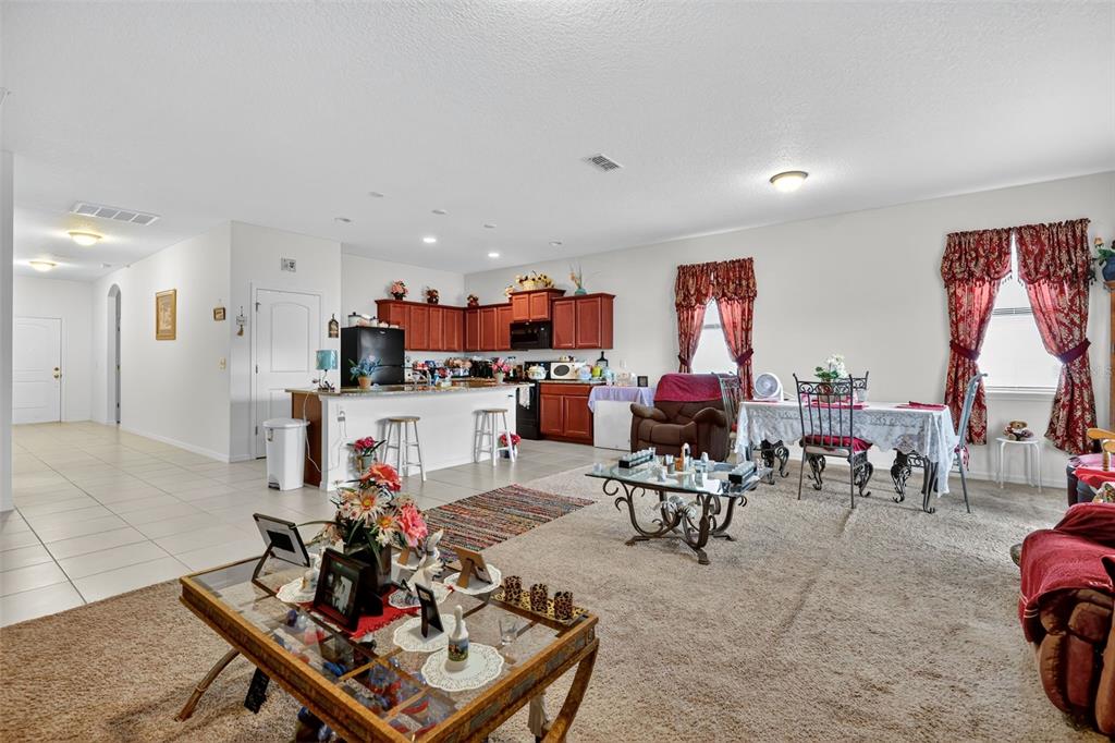 An open-concept living and dining area features carpeted floors, a kitchen island, and wood cabinetry — 508 DELTA AVENUE, GROVELAND, FL
