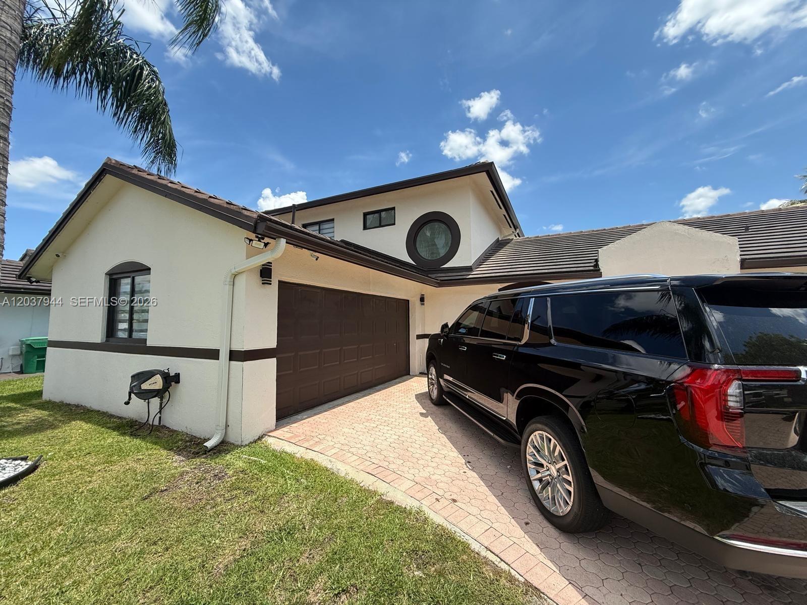 A black SUV is parked on a paved driveway in front of a two-story house — 14832 SW 169th Ln, Miami FL 33187, MIAMI, FL