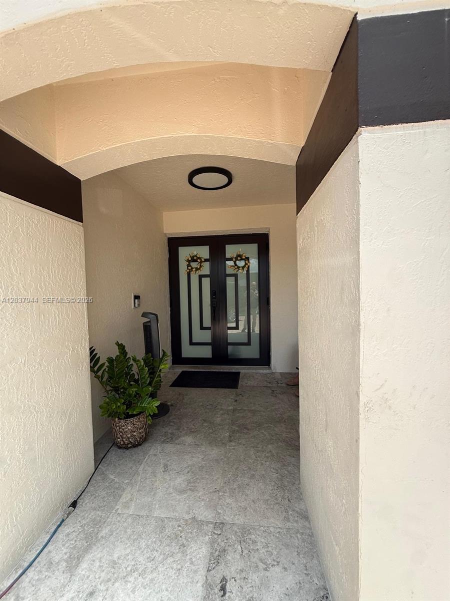 A covered entryway features a double glass door with geometric patterns and a potted plant — 14832 SW 169th Ln, Miami FL 33187, MIAMI, FL