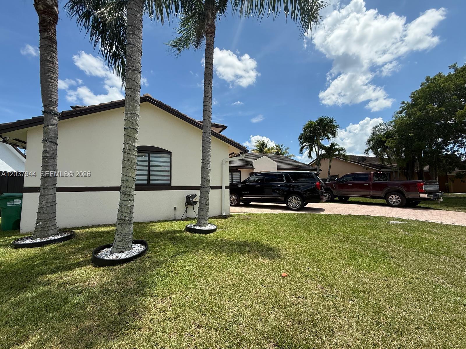 A single-story house with a lawn, palm trees, and two parked vehicles in the driveway — 14832 SW 169th Ln, Miami FL 33187, MIAMI, FL