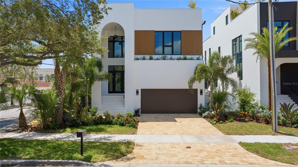 A modern two-story house features a white stucco facade, an arched entryway, and a brown garage — 130 ADRIATIC AVENUE, TAMPA, FL