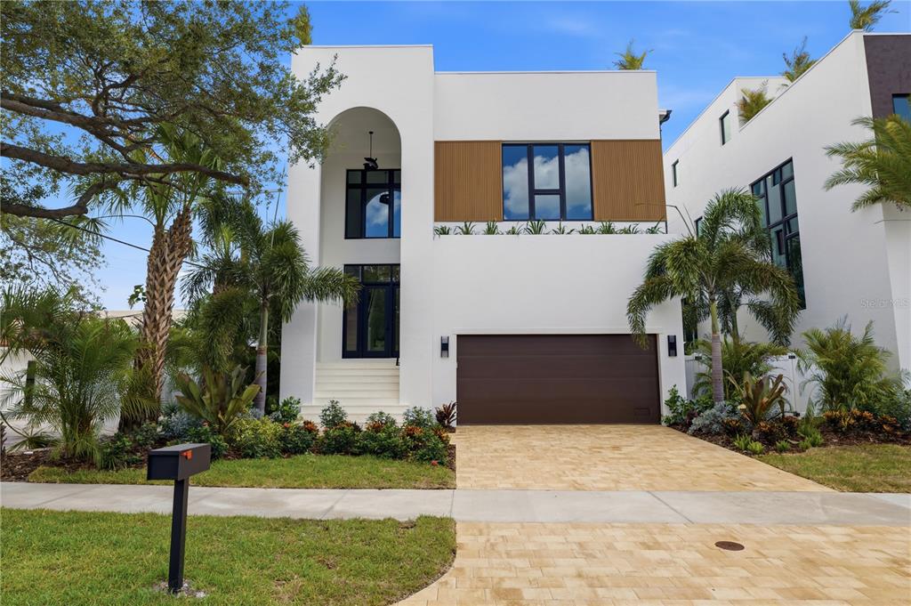 A modern two-story white house features a brown garage door, arched entryway, and landscaped front yard — 130 ADRIATIC AVENUE, TAMPA, FL