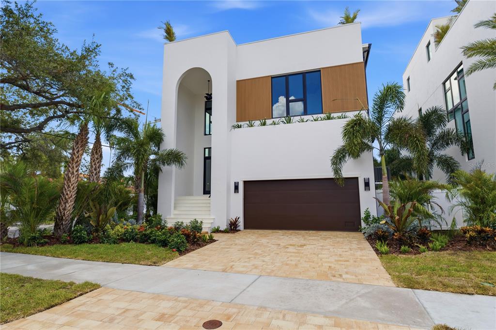 A modern two-story house with a white stucco facade, arched entryway, and brown garage door — 130 ADRIATIC AVENUE, TAMPA, FL