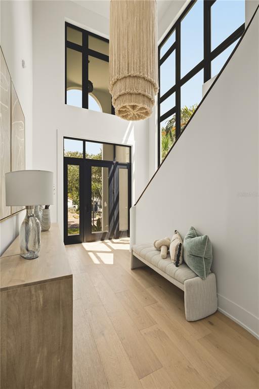 A bright entryway features a tall chandelier, a wooden console table, and a cushioned bench — 130 ADRIATIC AVENUE, TAMPA, FL