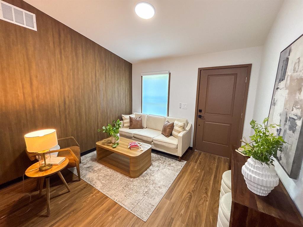 A living room features wood-look flooring, a wood-paneled accent wall, a sofa, and a coffee table — 5830 VIRTUDES STREET, SEBRING, FL