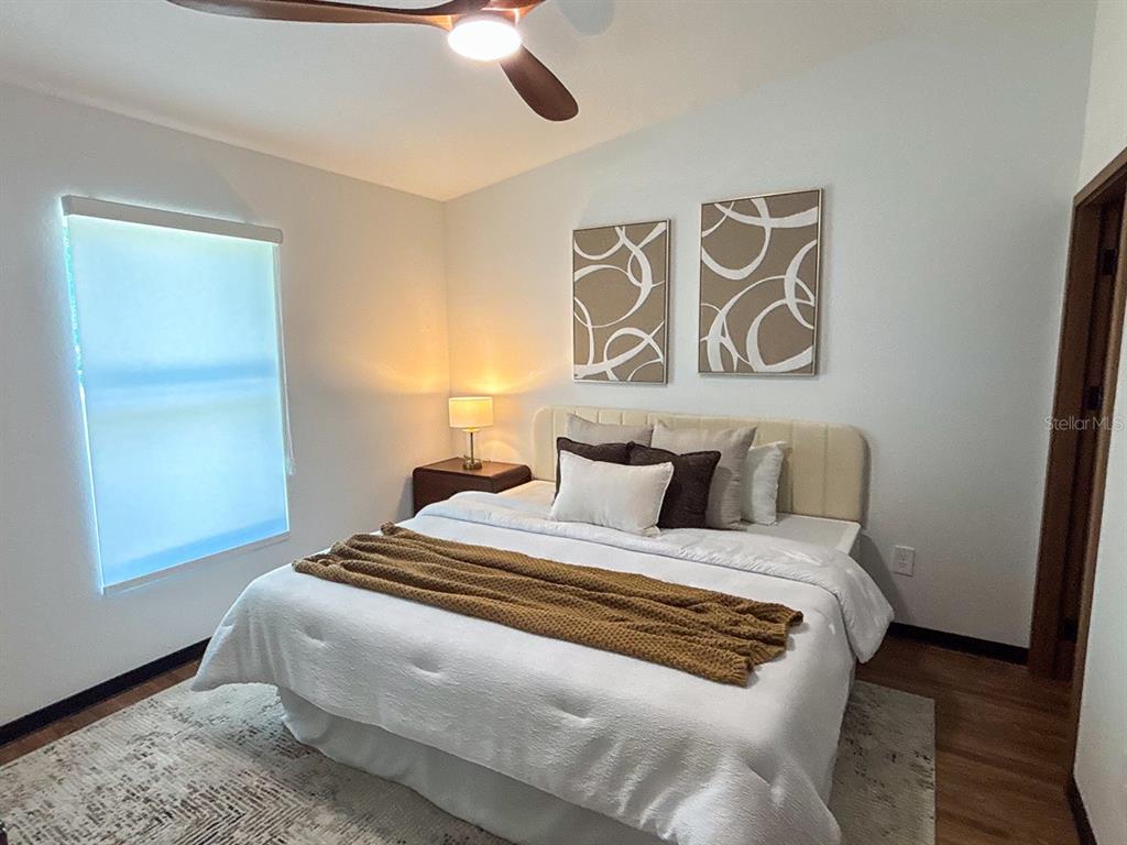 A bedroom features a bed with white bedding, a mustard throw, and two abstract wall prints — 5830 VIRTUDES STREET, SEBRING, FL