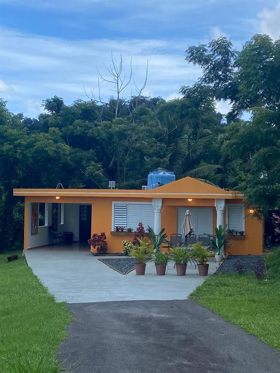 A single-story orange house with a carport, front porch, and a blue water tank — Aguas Buenas 5.9 795 SECTOR GARAY, AGUAS BUENAS, PR