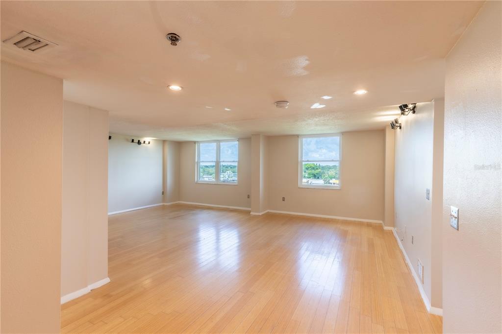 A bright, empty room with light wood flooring, recessed lighting, and two windows — 701 S MADISON AVENUE UNIT 502, CLEARWATER, FL
