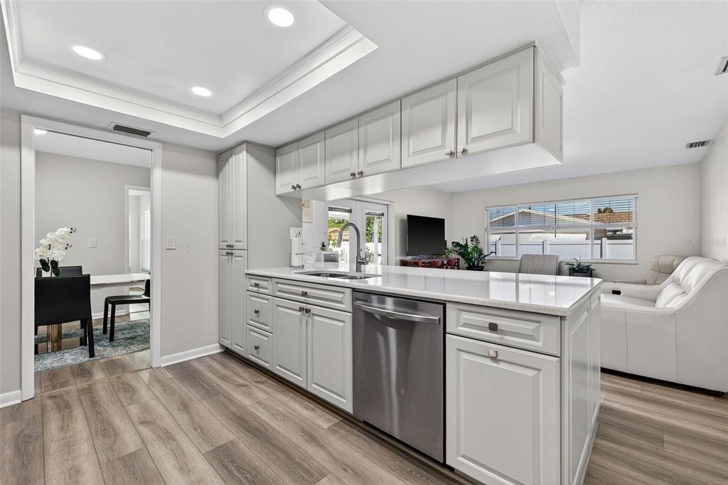A kitchen with white cabinets, stainless steel appliances, and light wood-look flooring — 10275 113TH STREET, SEMINOLE, FL