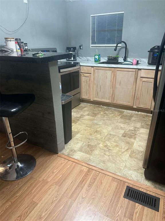 A kitchen features light wood cabinets, a black countertop, and a breakfast bar — 10809 SE 129TH STREET, BELLEVIEW, FL