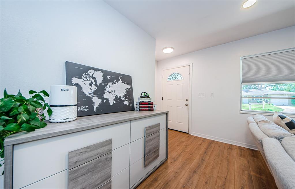 A living room features a white and wood-grain dresser, a world map, and a front door — 7241 56TH AVENUE N, ST PETERSBURG, FL