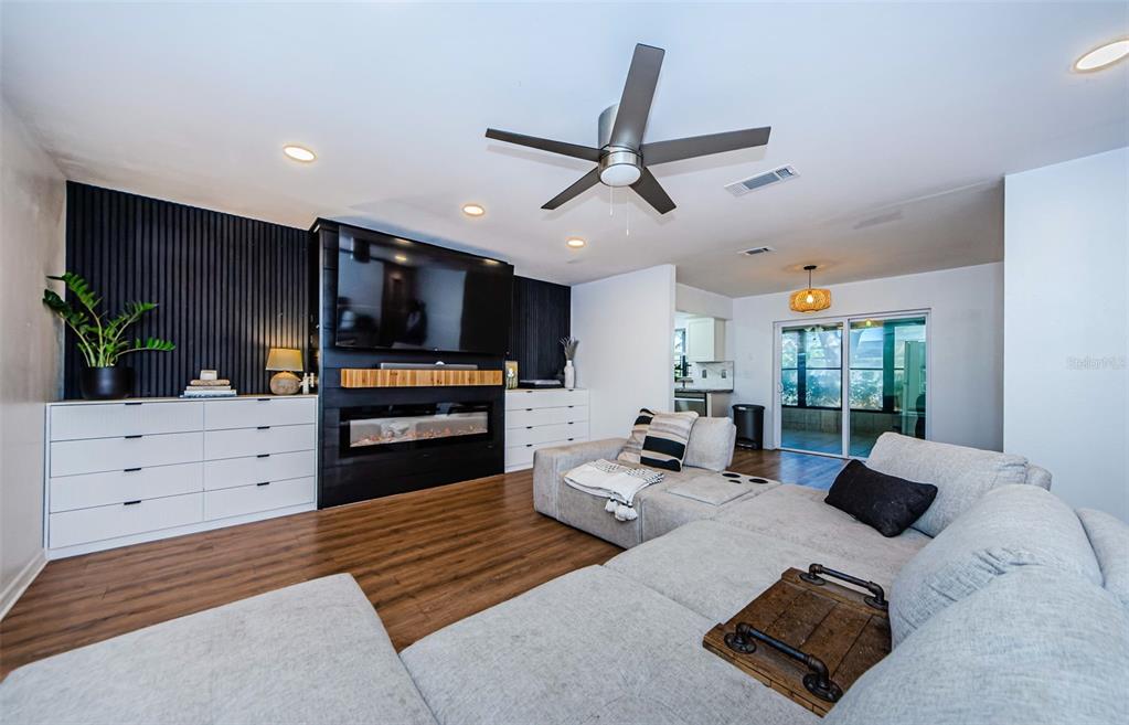 A living room features a large sectional sofa, a wall-mounted television, and a built-in fireplace — 7241 56TH AVENUE N, ST PETERSBURG, FL