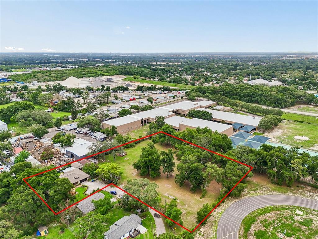 An aerial view shows a large, tree-filled residential lot outlined in red next to buildings — 5105 N 45TH STREET, TAMPA, FL