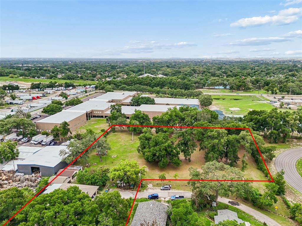 An aerial view shows a vacant, tree-filled lot outlined in red next to a large building — 5105 N 45TH STREET, TAMPA, FL