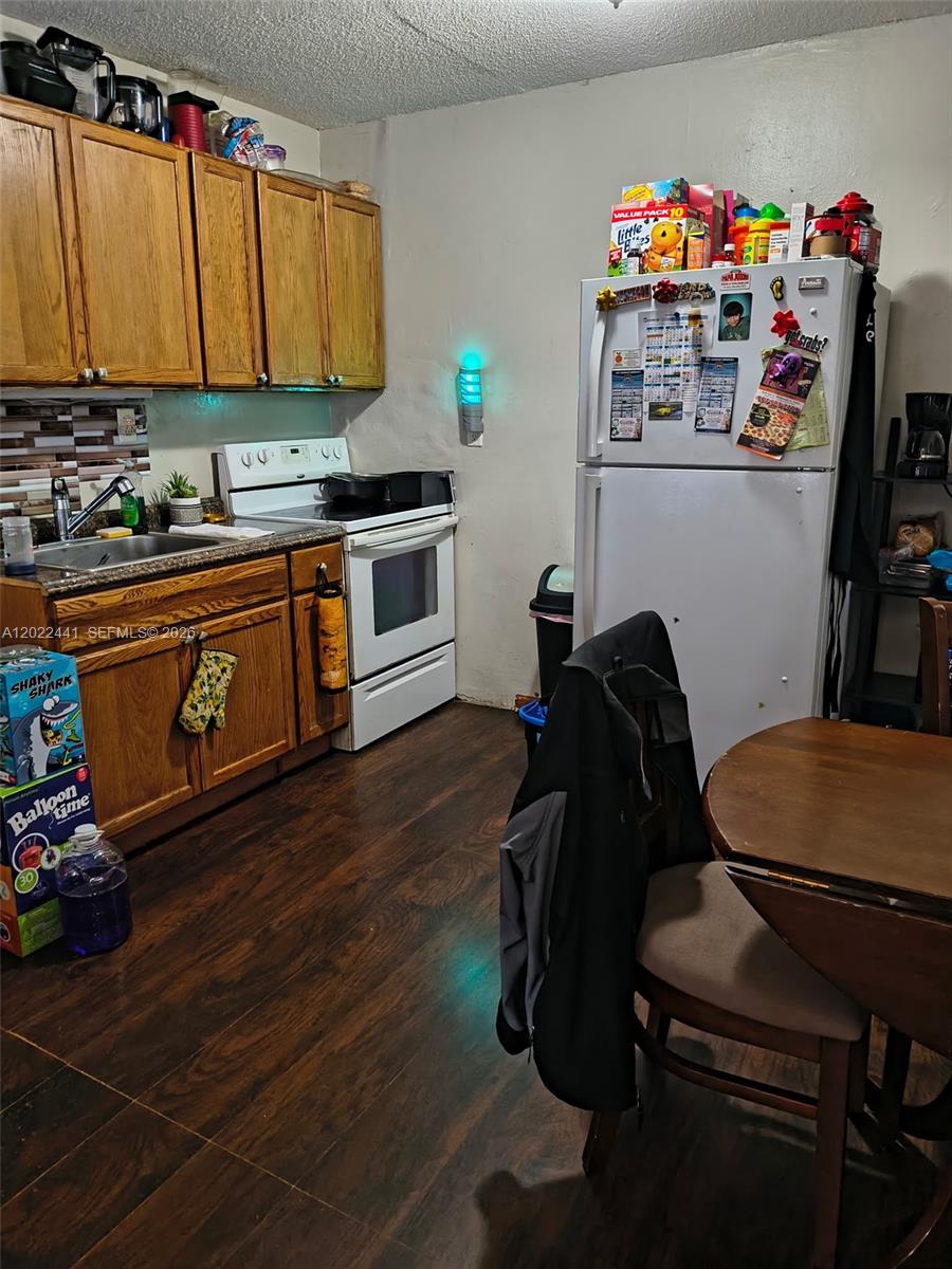 A kitchen features wood cabinets, a white stove, a white refrigerator, and dark wood flooring — 6316 Pierce St, Hollywood FL 33024, HOLLYWOOD, FL