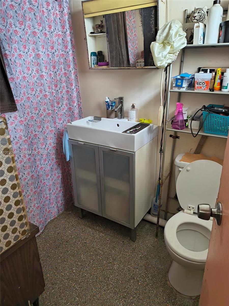 A bathroom features a floral shower curtain, a white pedestal sink, and a toilet — 6316 Pierce St, Hollywood FL 33024, HOLLYWOOD, FL