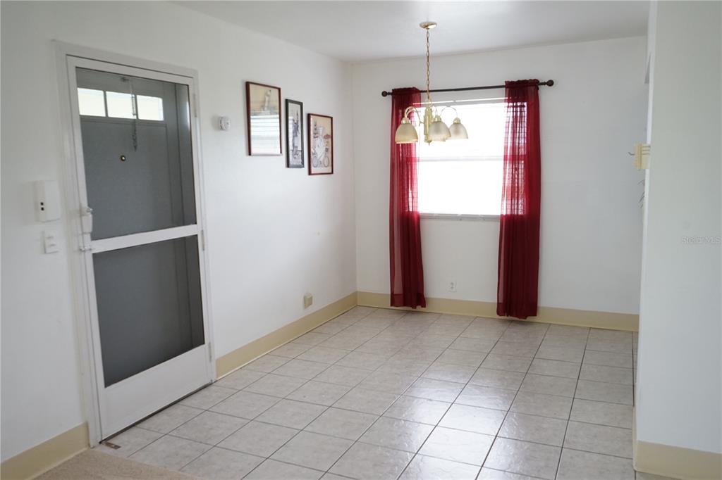A dining area with white walls, tiled floors, a chandelier, and a window with curtains — 101 CAMBRIDGE TRL UNIT 205, SUN CITY CENTER, FL