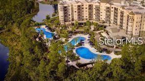 An aerial view of a multi-story apartment complex featuring outdoor swimming pools and a lake — 14501 GROVE RESORT AVENUE UNIT 1637, WINTER GARDEN, FL