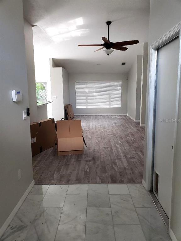 An entryway with marble flooring leads into a living area featuring wood-look floors and a ceiling fan — 4808 LIMERICK DRIVE, TAMPA, FL