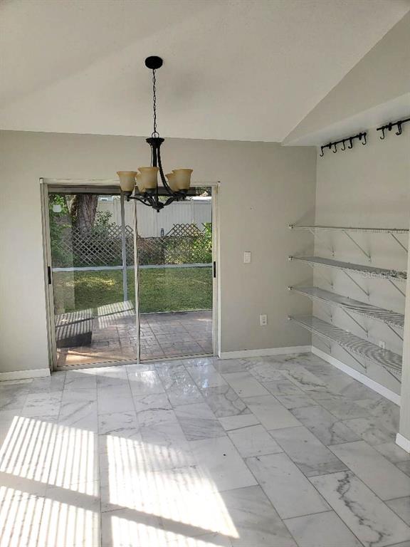 A dining area features marble tile flooring, a chandelier, wall-mounted shelving, and sliding glass doors — 4808 LIMERICK DRIVE, TAMPA, FL