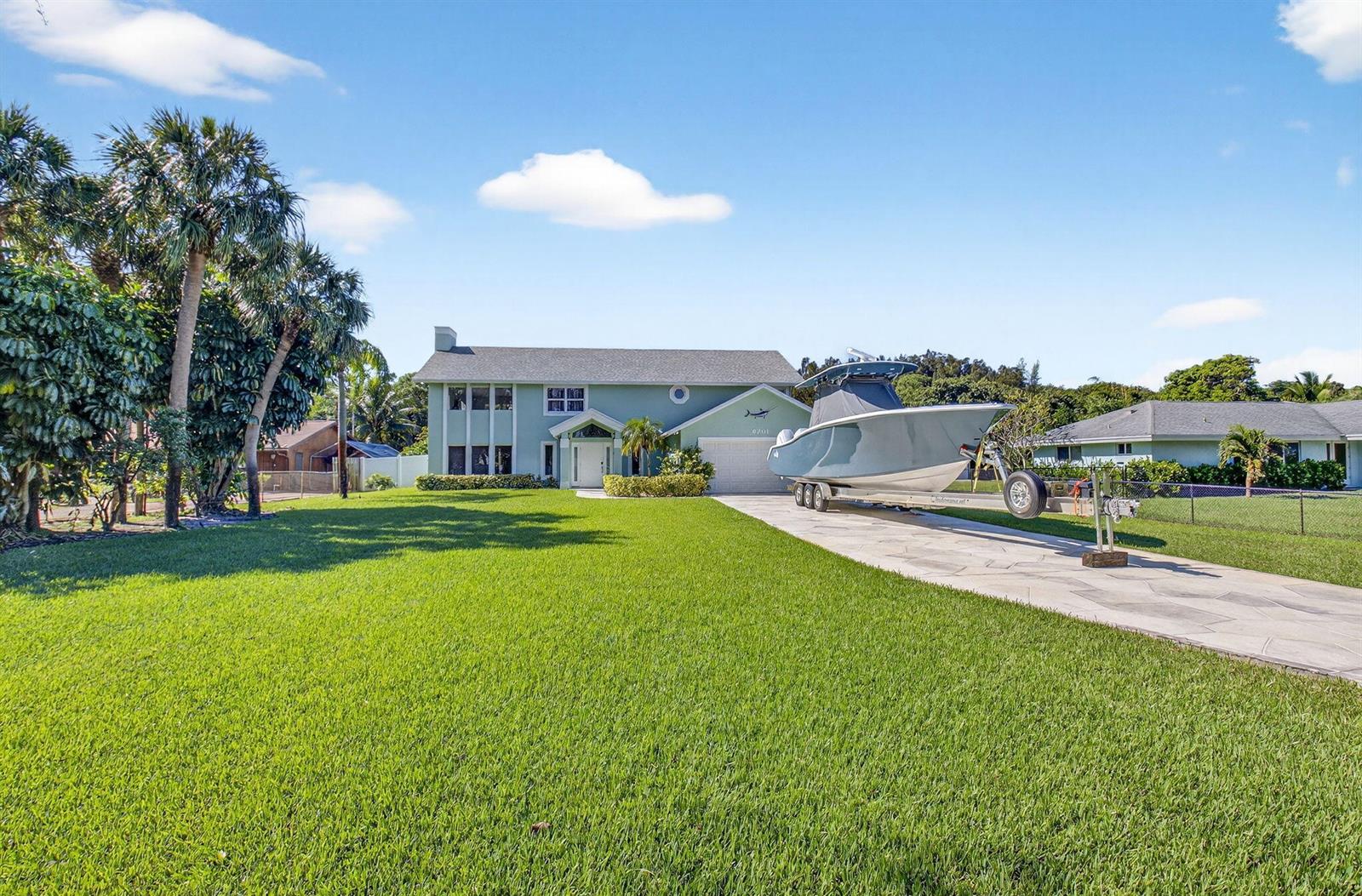 A light green two-story house with a boat on a trailer in the driveway — 6701 Hillside Lane, Lake Worth FL 33462, LAKE WORTH, FL
