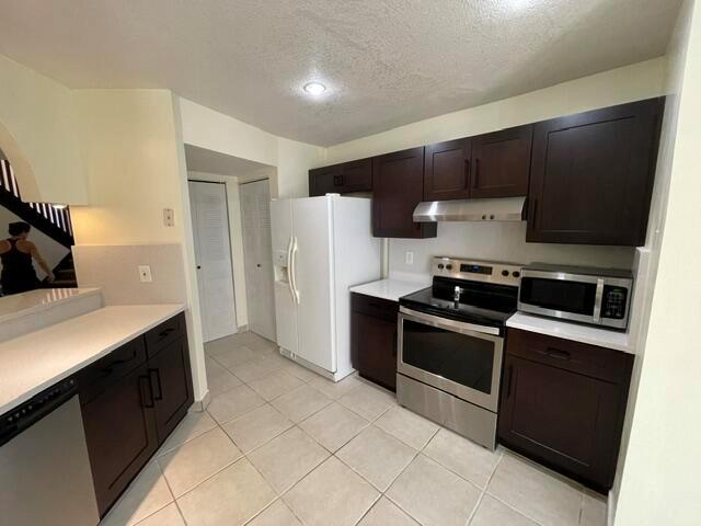 A kitchen features dark wood cabinets, stainless steel appliances, white countertops, and light tile flooring — 9321 W Sunrise Boulevard, Plantation FL 33322, PLANTATION, FL