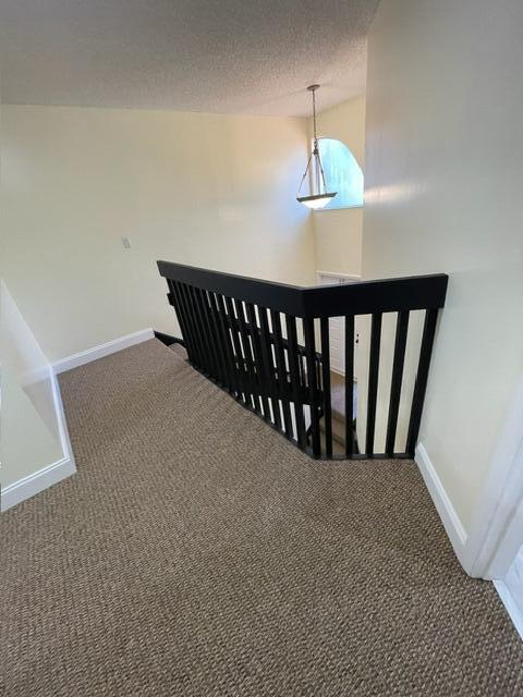 A carpeted hallway features a black wooden railing overlooking a staircase with a hanging light — 9321 W Sunrise Boulevard, Plantation FL 33322, PLANTATION, FL