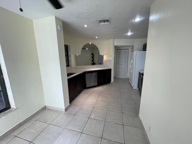 A kitchen features dark cabinetry, light tile flooring, and an arched pass-through window — 9321 W Sunrise Boulevard, Plantation FL 33322, PLANTATION, FL