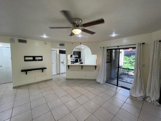 A living room with tile floors, a ceiling fan, and an open kitchen pass-through window — 9321 W Sunrise Boulevard, Plantation FL 33322, PLANTATION, FL