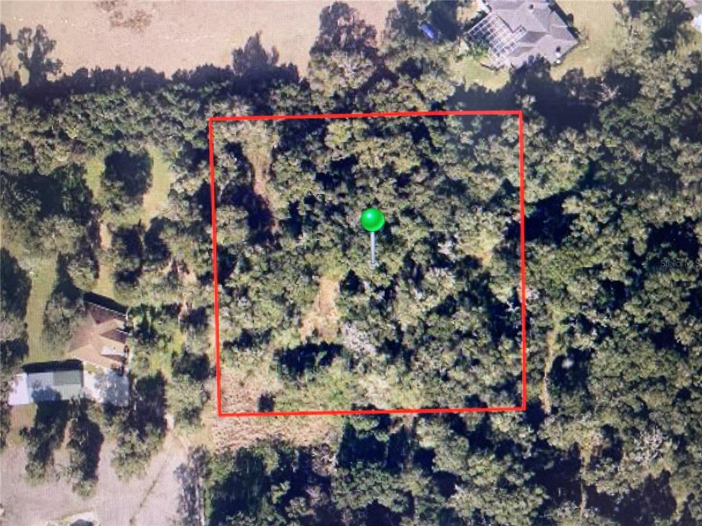 An aerial view shows a wooded, rectangular plot of land marked with a green pin — OAK VALLEY DRIVE, DELAND, FL