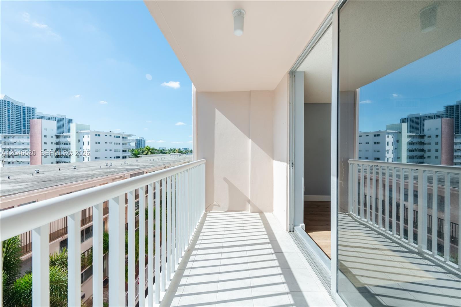 A balcony with white railings overlooks a residential area under a clear blue sky — 3161 S Ocean Dr # 407, Hallandale Beach FL 33009, HALLANDALE BEACH, FL