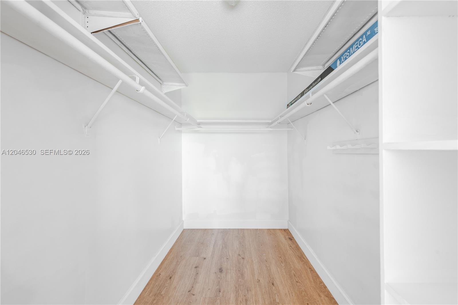 A walk-in closet features white walls, wood-look flooring, and white wire shelving units — 3161 S Ocean Dr # 407, Hallandale Beach FL 33009, HALLANDALE BEACH, FL