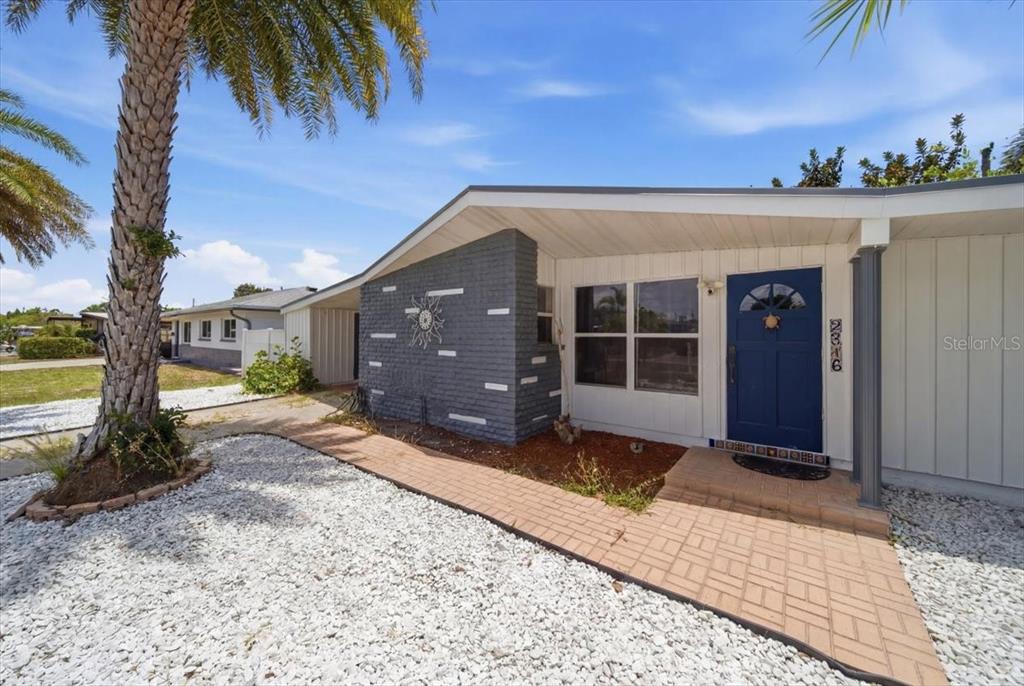 A single-story house features a blue front door, a gray brick accent wall, and white siding — 2316 HOLYOKE AVENUE, BRADENTON, FL