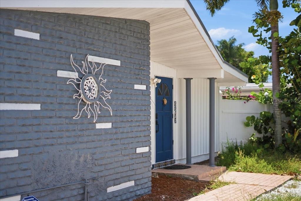 A gray brick exterior wall with a sun decoration and a blue front door — 2316 HOLYOKE AVENUE, BRADENTON, FL