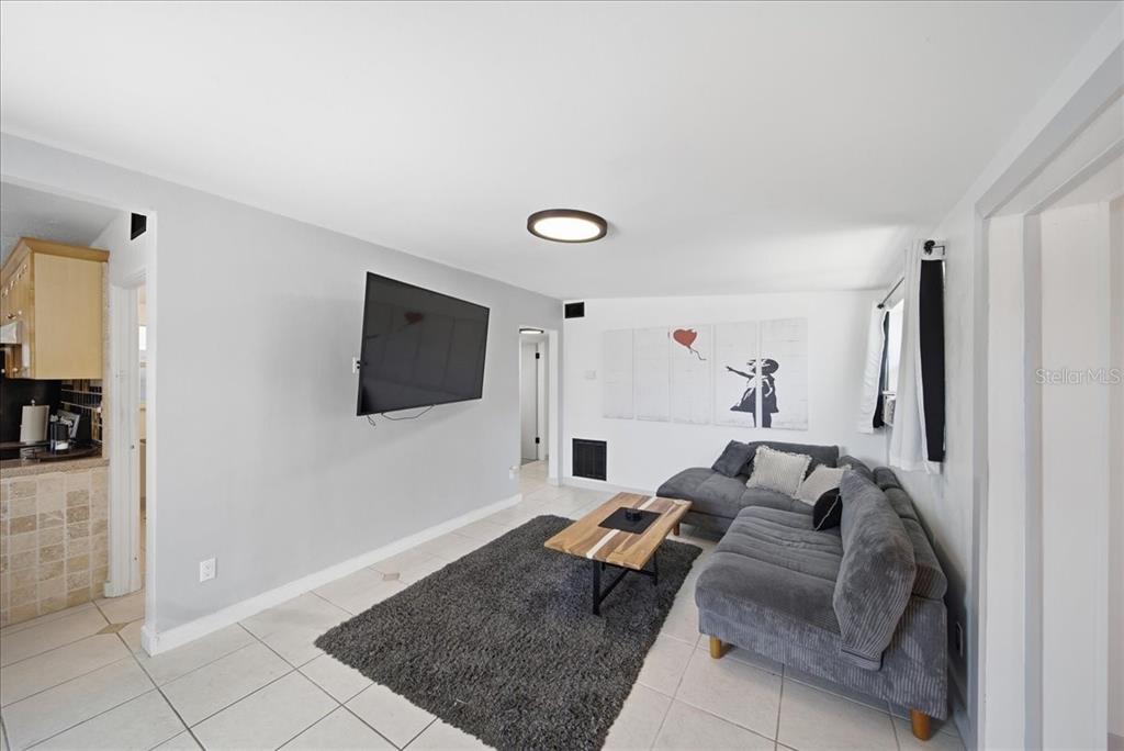 A living room features a gray sectional sofa, a coffee table, and a wall-mounted television — 2316 HOLYOKE AVENUE, BRADENTON, FL