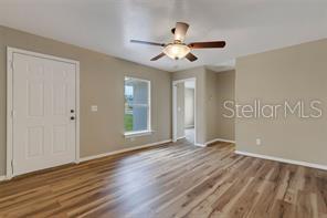 An empty room features wood-look flooring, a ceiling fan, a white door, and two windows — 3100 W REYNOLDS STREET, PLANT CITY, FL