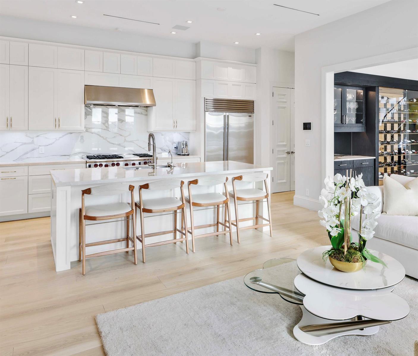 A modern white kitchen features a marble backsplash, stainless steel appliances, and a central island — 5501 S Flagler Drive, West Palm Beach FL 33405, WEST PALM BEACH, FL