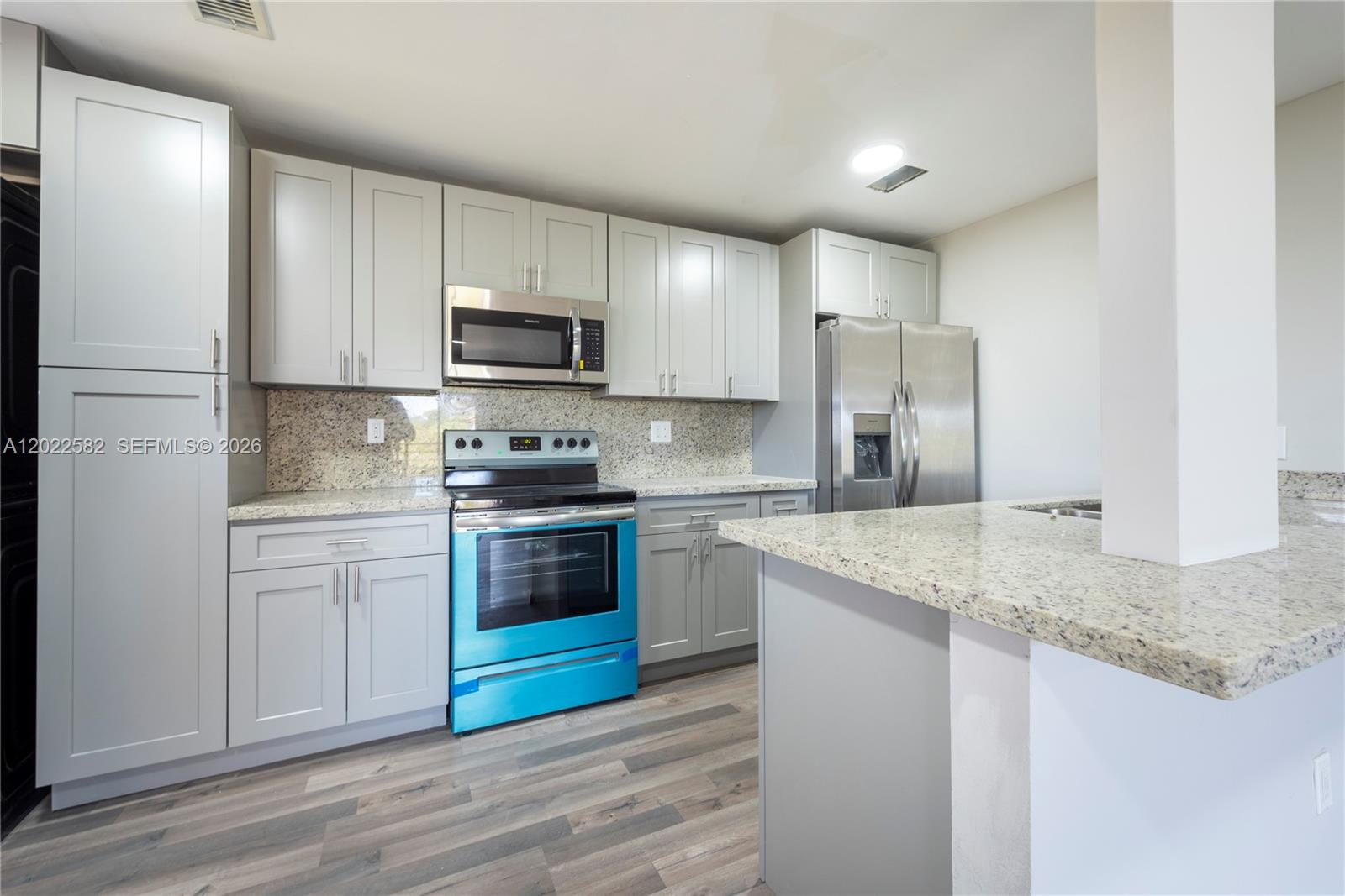 A kitchen features gray cabinets, granite countertops, stainless steel appliances, and a bright blue oven — 4111 Stirling Rd # 509, Dania Beach FL 33314, DANIA BEACH, FL