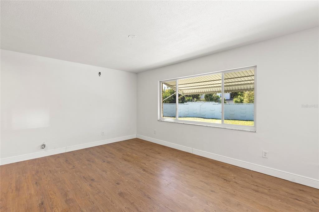 An empty room with white walls, wood-look flooring, and a large window — 250 NW ROSERY ROAD UNIT 314, LARGO, FL