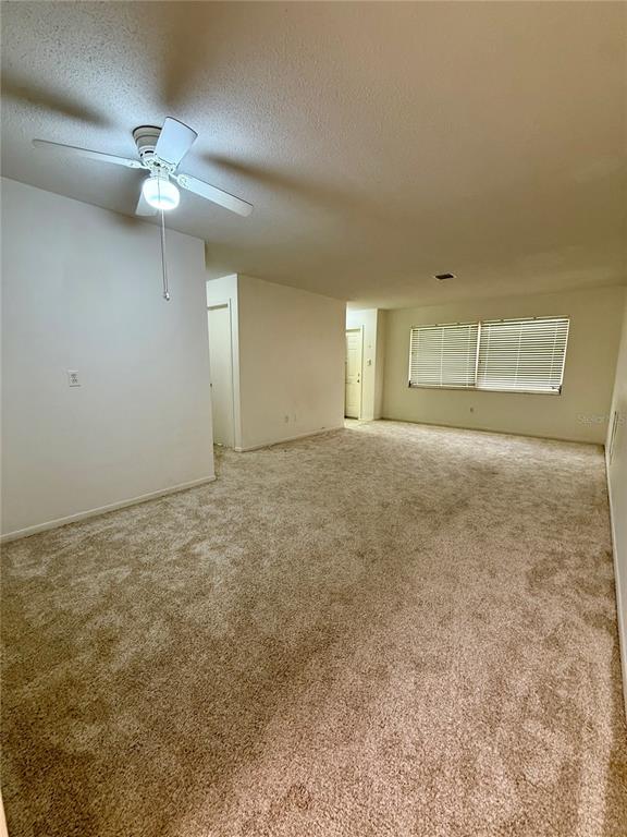 This virtually staged living room features beige carpeting, white walls, and a dining area — 6775 ARMAND PLACE N UNIT 4, PINELLAS PARK, FL